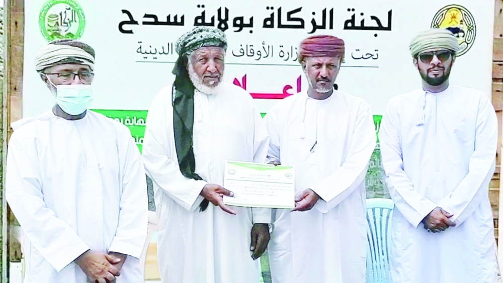 رئيس لجنة الزكاة يسلم شهادة للفائز بالمزاد