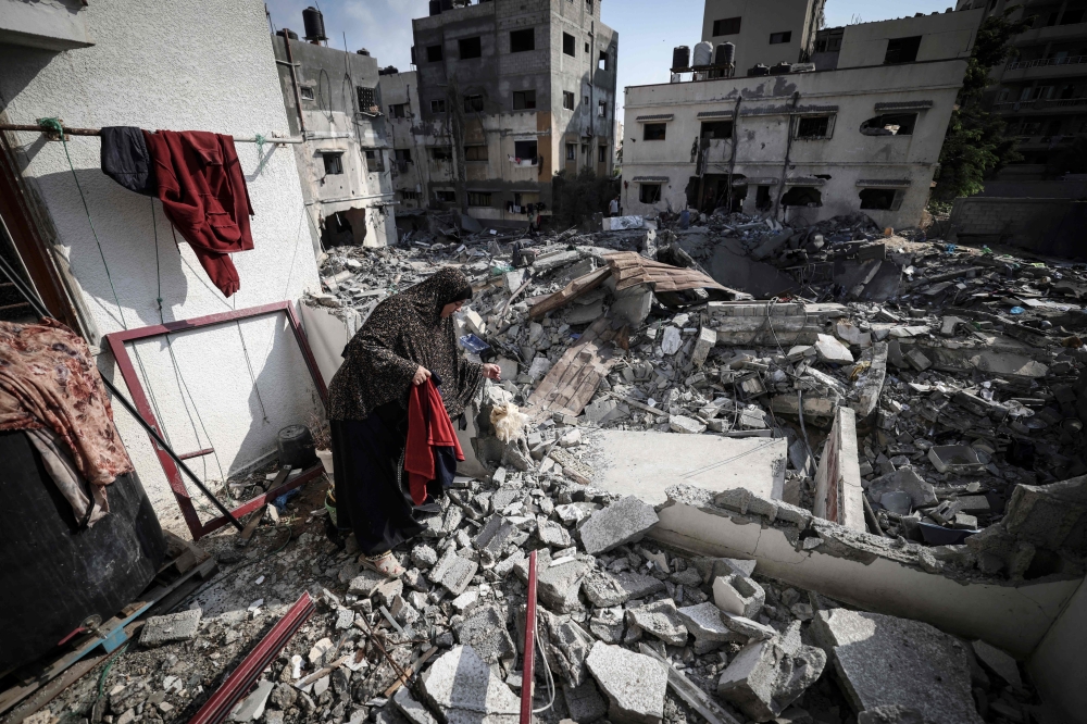 امرأة فلسطينية تبحث في الأنقاض حول منزلها الذي تضرر بشدة خلال الضربات الجوية الإسرائيلية في مدينة غزة أمس.
"أ ف ب"