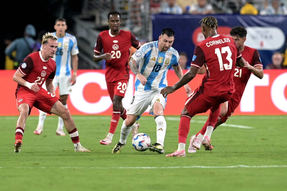 ليونيل ميسي لاعب الأرجنتين يحتفظ بالكرة وسط متابعة من لاعبي كندا   «أ.ف.ب»