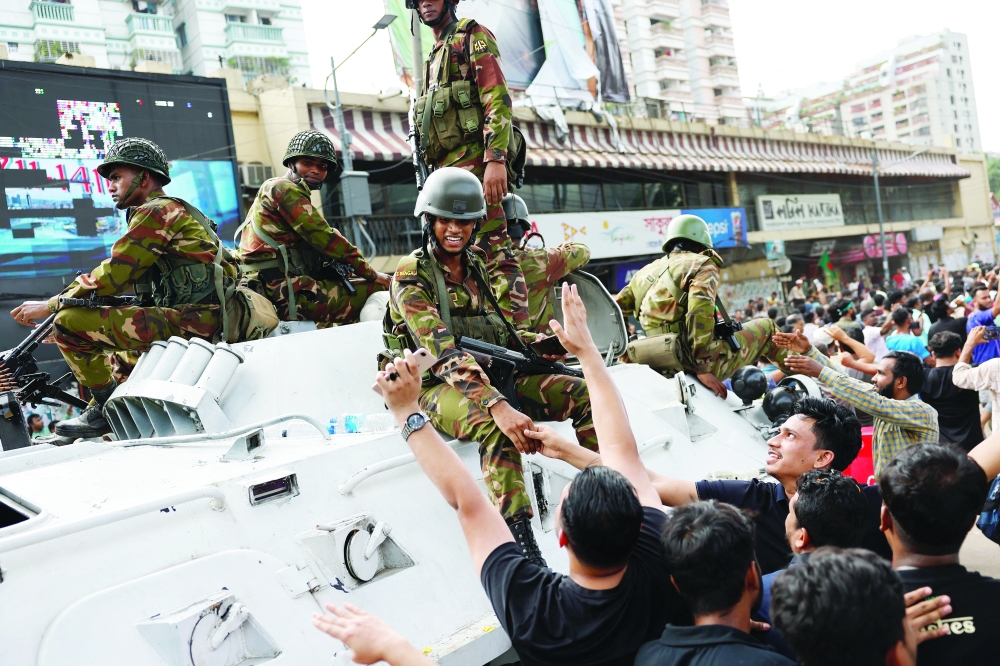 جموع المواطنيين يتصافحون عدد من أفراد الجيش أثناء احتفالهم بسقوط حكم الشيخة حسينة الذي دام نحو خمسة عشر عاما. رويترز 