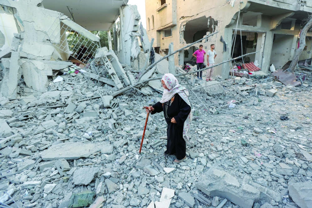 إمرأة فلسطينية تسير أمام منازل مدمرة في موقع غارة  في دير  وسط قطاع غزة