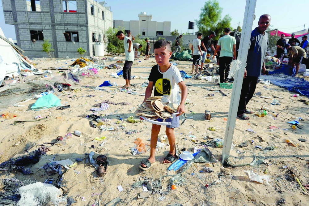 طفل فلسطيني يحمل صينية بها خبز في مخيم المواصي في خان يونس بعد قصف إسرائيلي ليلي 