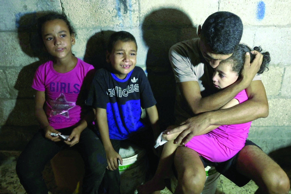 فلسطيني يحتضن ابنته بالقرب من جثمان أحد أقاربهم قُتل خلال غارة إسرائيلية على مدرسة عمرو بن العاص التي تؤوي الفلسطينيين النازحين في حي الشيخ رضوان بمدينة غزة