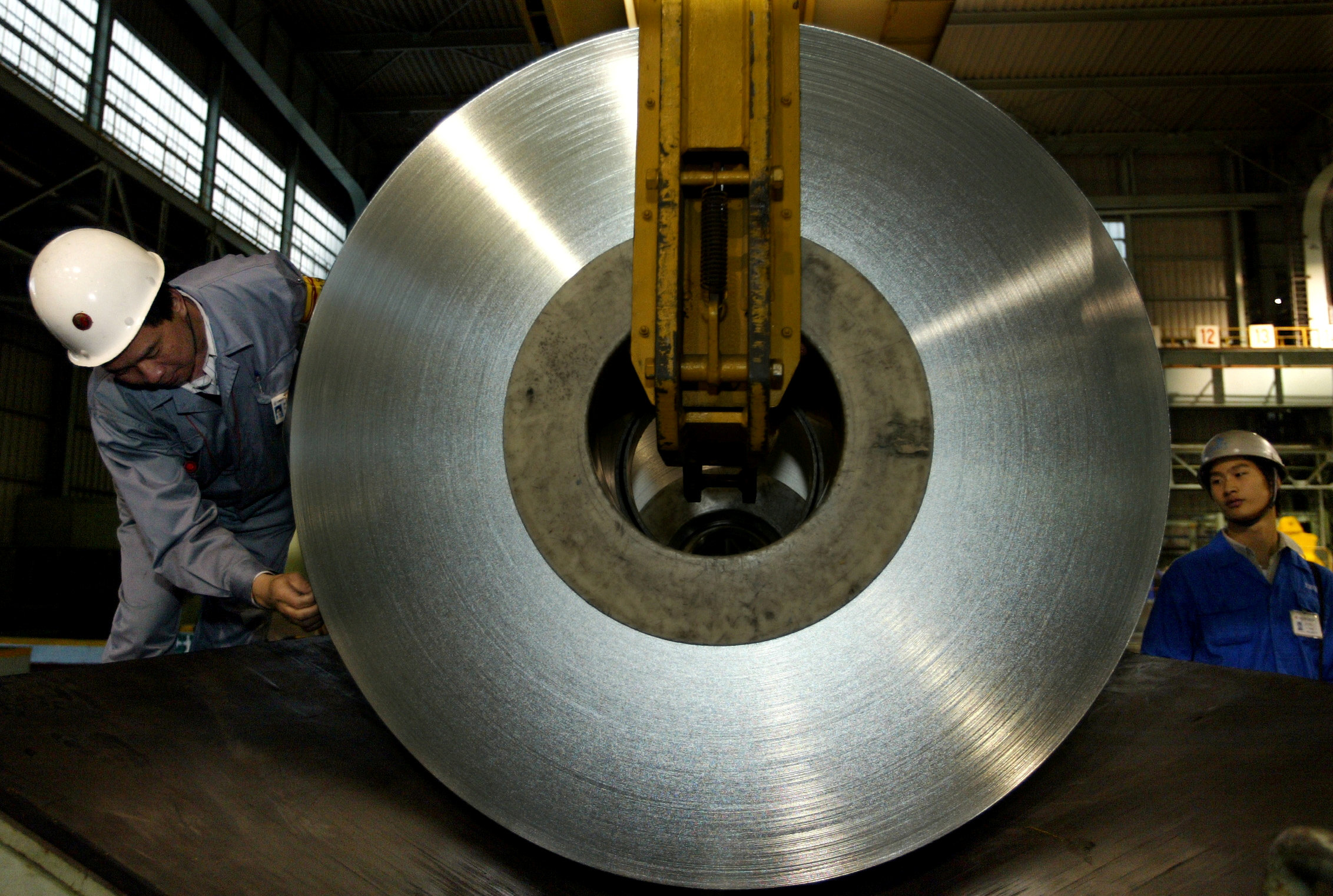FILE PHOTO -  Chinese workers unload a roll of tin plate at Baosteel plant on the outskirts of Shanghai