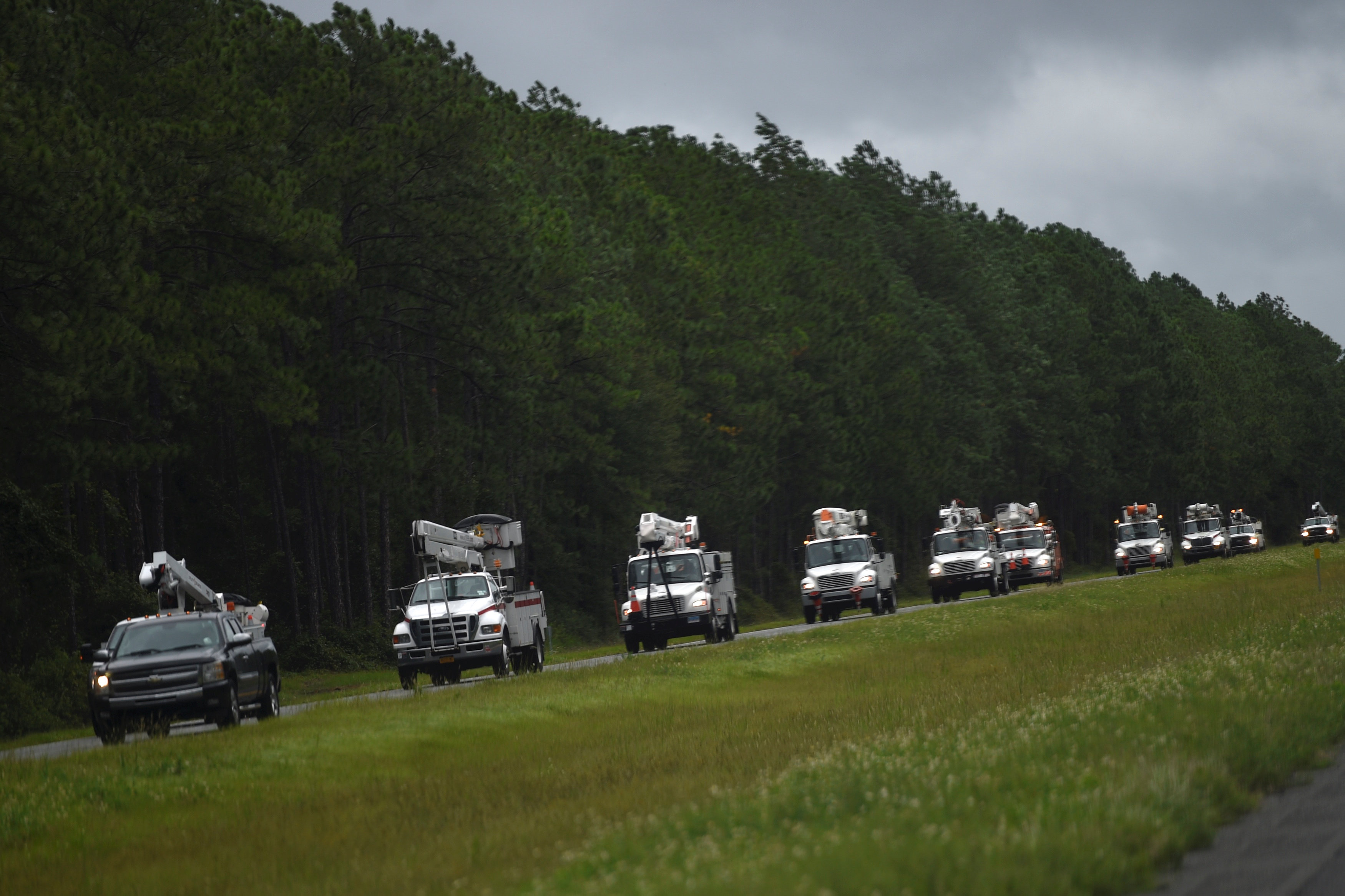 A line of utility trucks drive north on Interstate 75