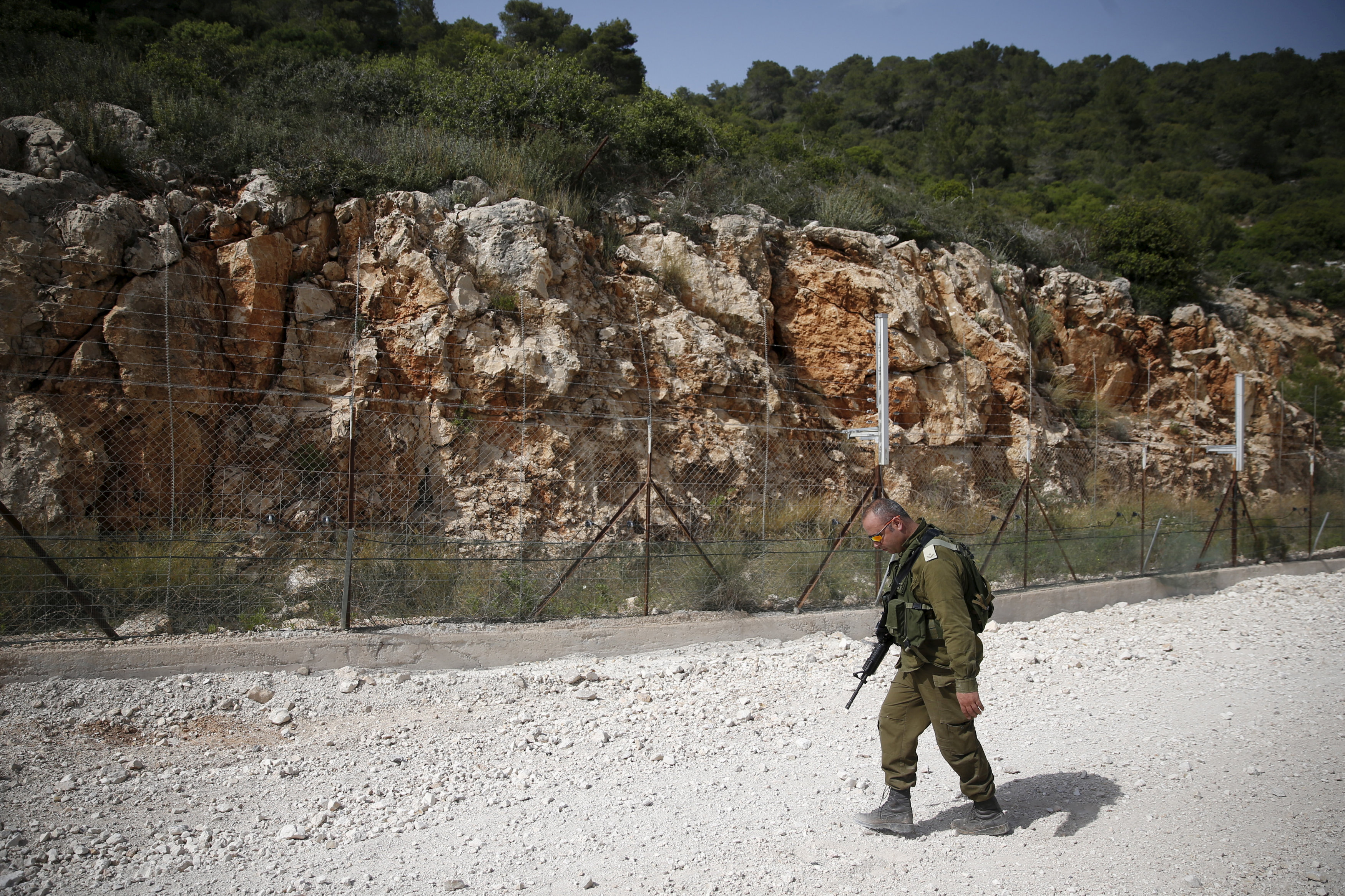 FILE PHOTO: An Israeli soldier walks near the area where the Israeli army is excavating part of a cliff to create an additional barrier along its border with Lebanon, near the community of Shlomi in northern Israel