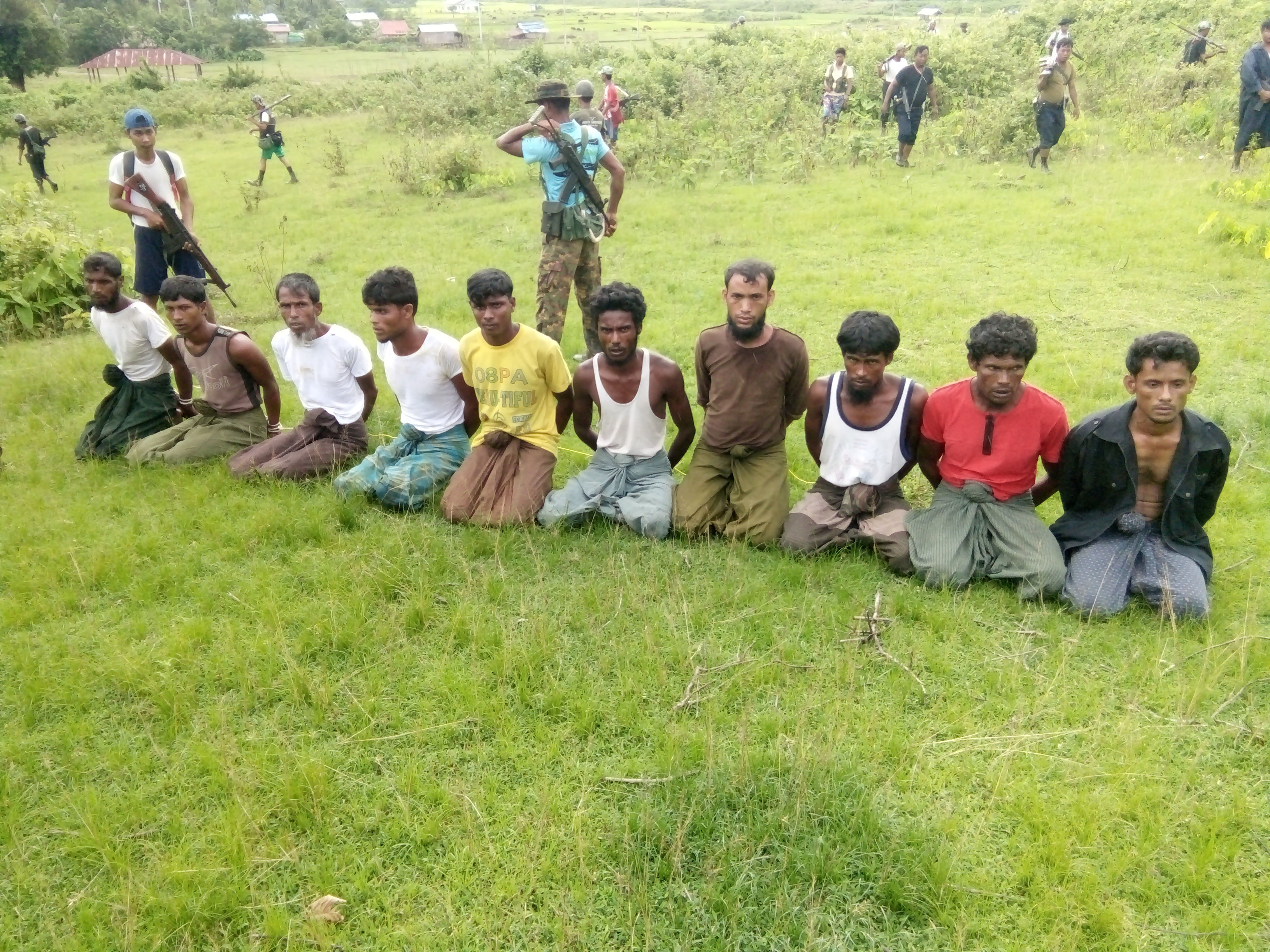 Ten Rohingya Muslim men with their hands bound kneel as members of the Myanmar security forces stand guard in Inn Din village
