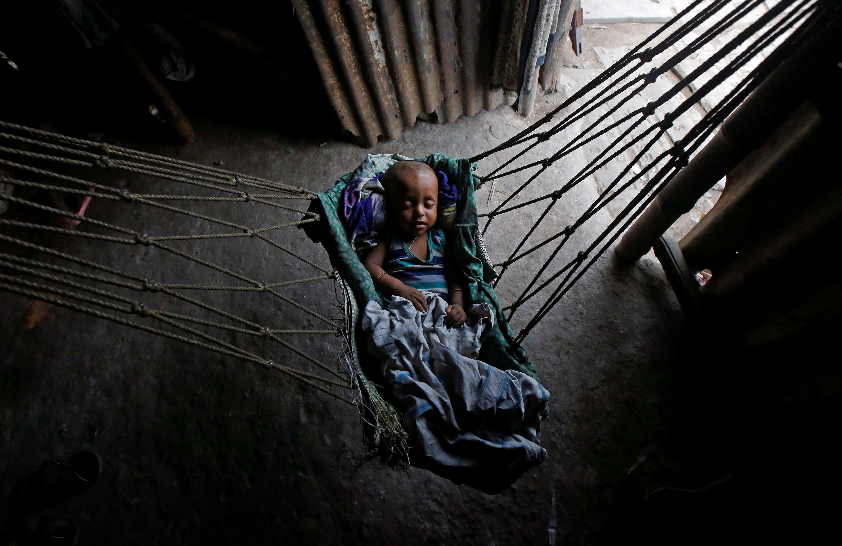 An infant sleeps in a hammock at a makeshift shelter in Kolkata
