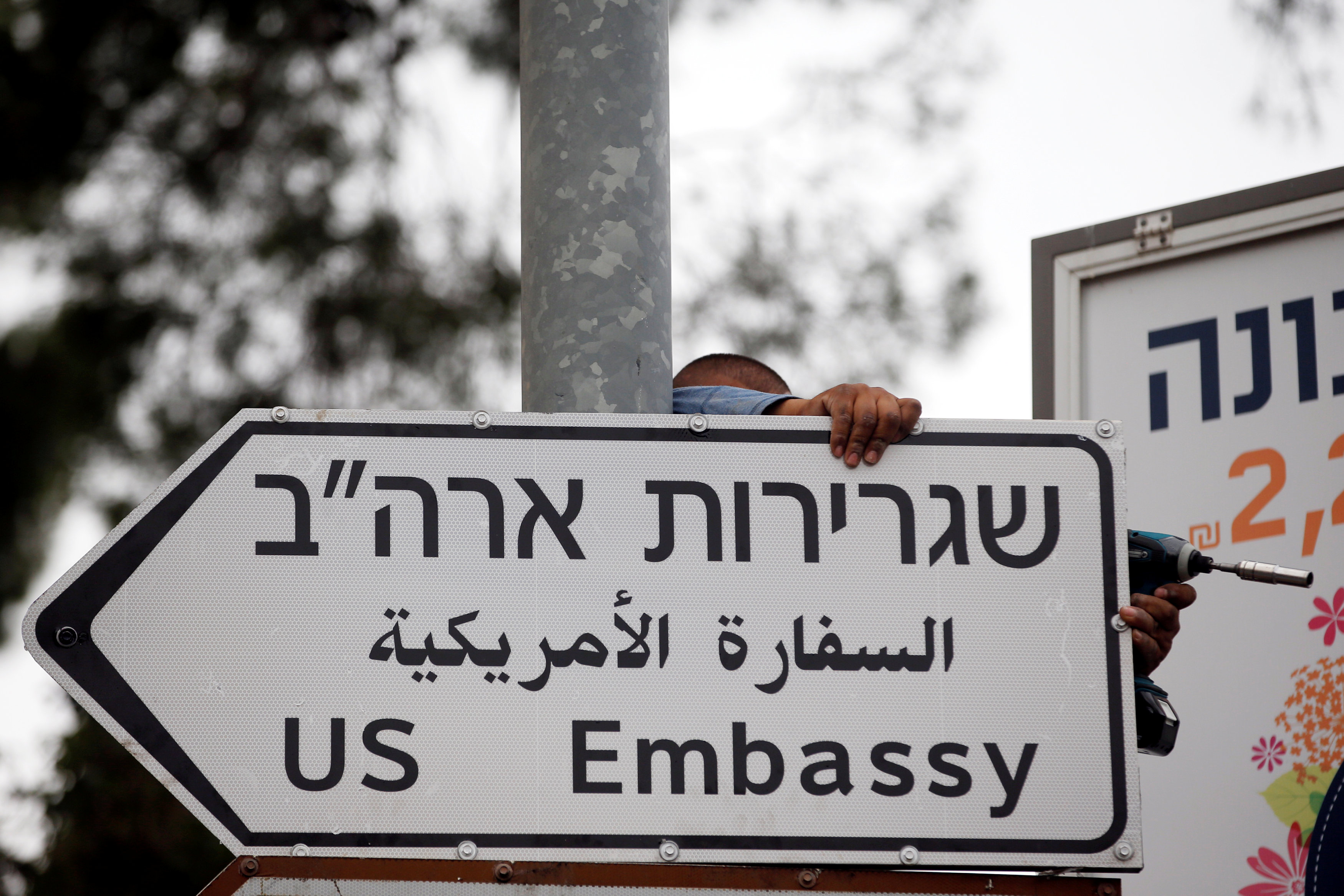 FILE PHOTO: A worker hangs a road sign directing to the U.S. embassy, in the area of the U.S. consulate in Jerusalem