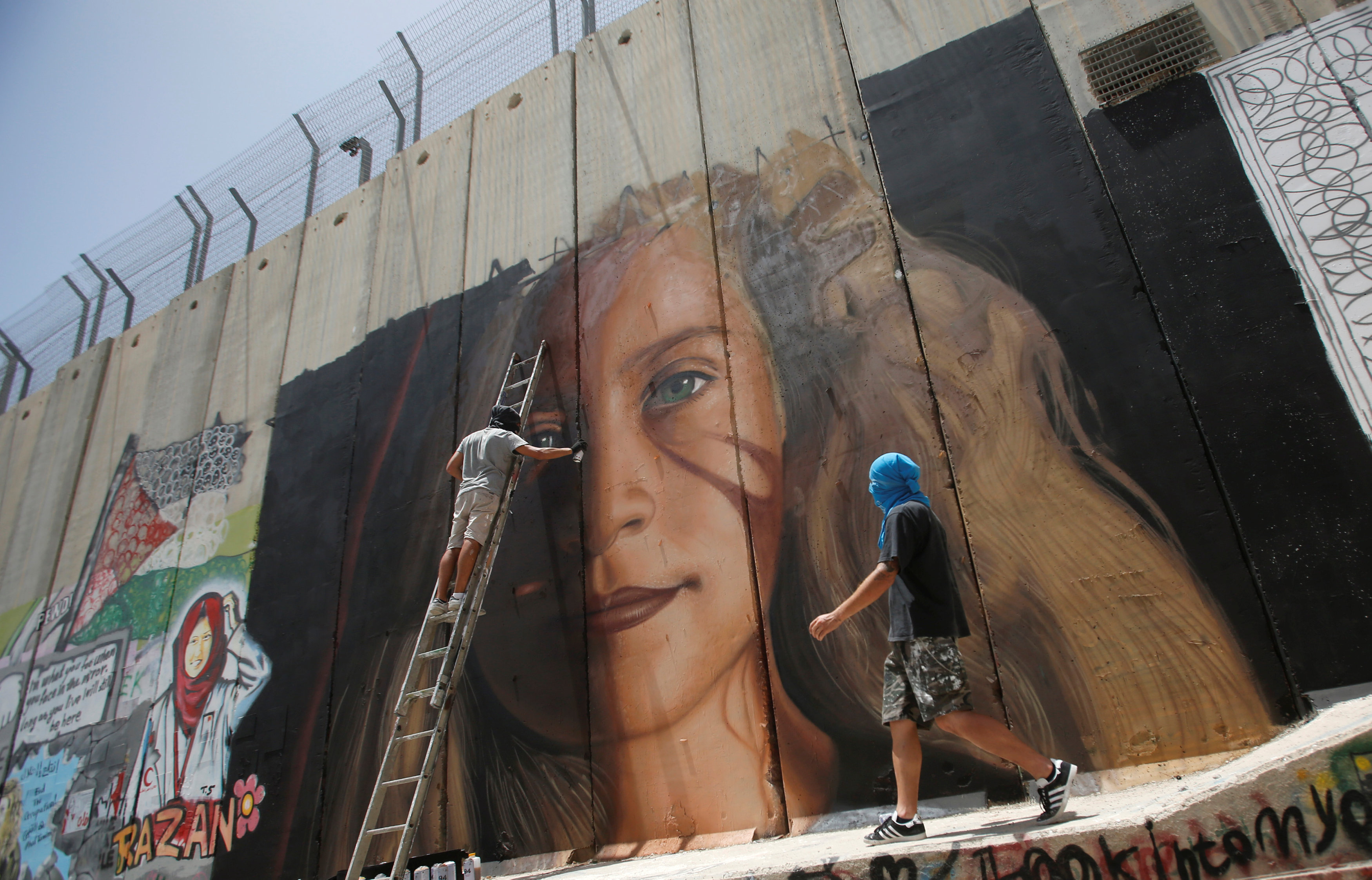 Foreign artist paints on the Israeli wall a mural depicting Palestinian teen Ahed Tamimi who is detained by Israel, in Bethlehem, in the occupied West Bank