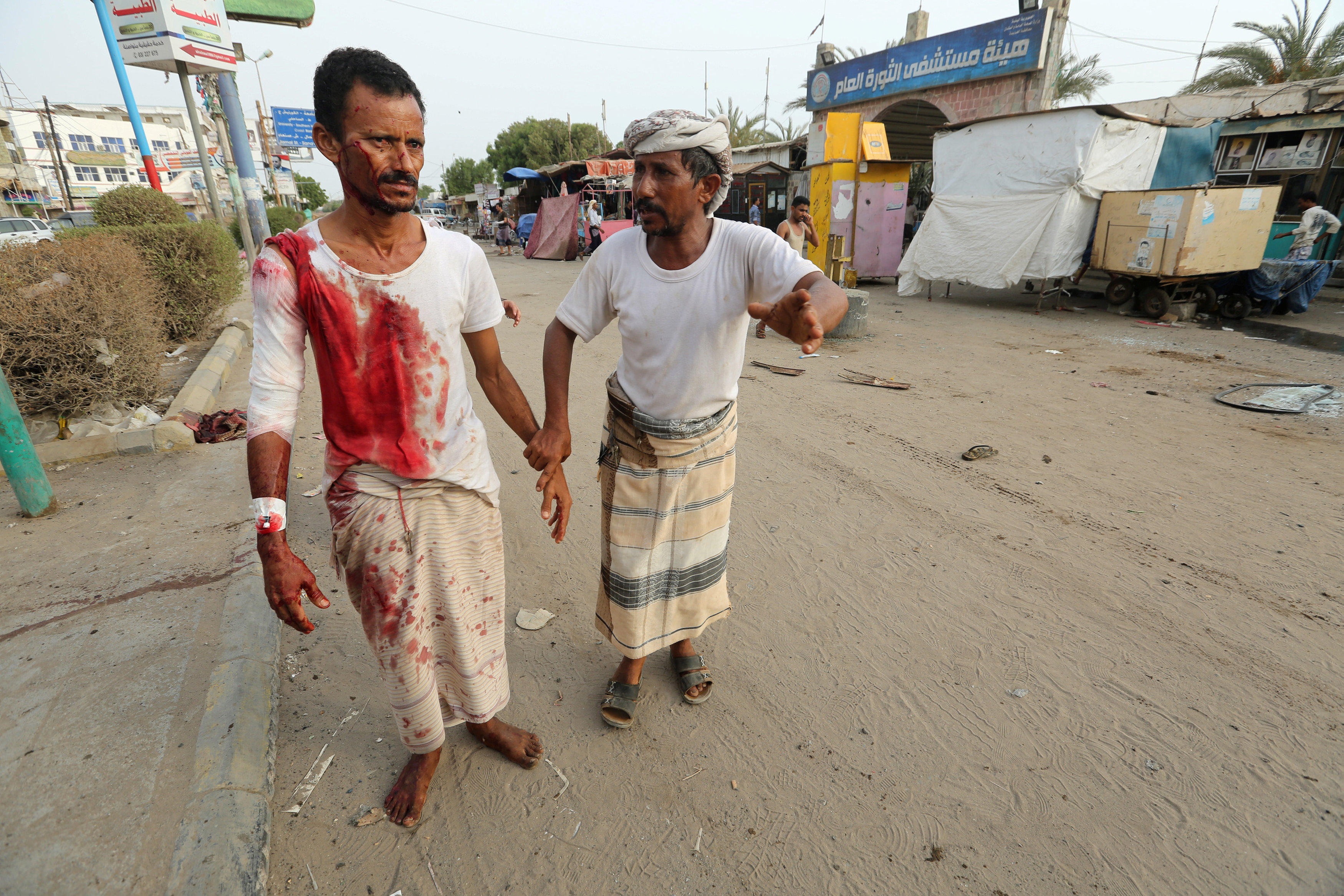 Man injured by an air strike at a fish market strike is helped by another man near al-Thawra Hospital in Hodeidah