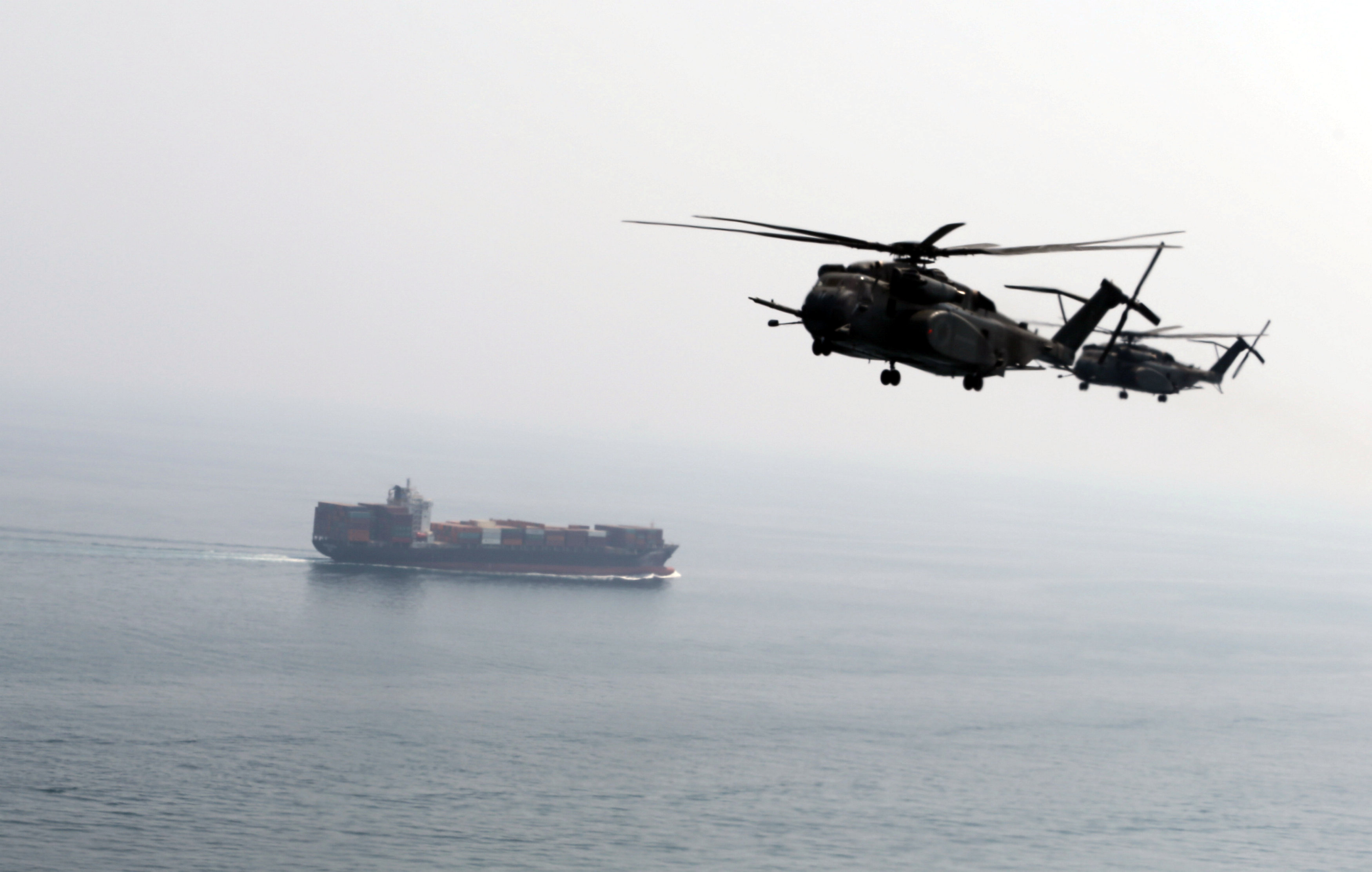 U.S. Navy MH-53E Sea Dragon helicopters are seen making their way to an exercise area as they take part in a U.S. and U.K. Mine Countermeasures Exercise (MCMEX) taking place at the Arabian Sea, as a cargo ship is seen sailing towards Straits of Harmoz