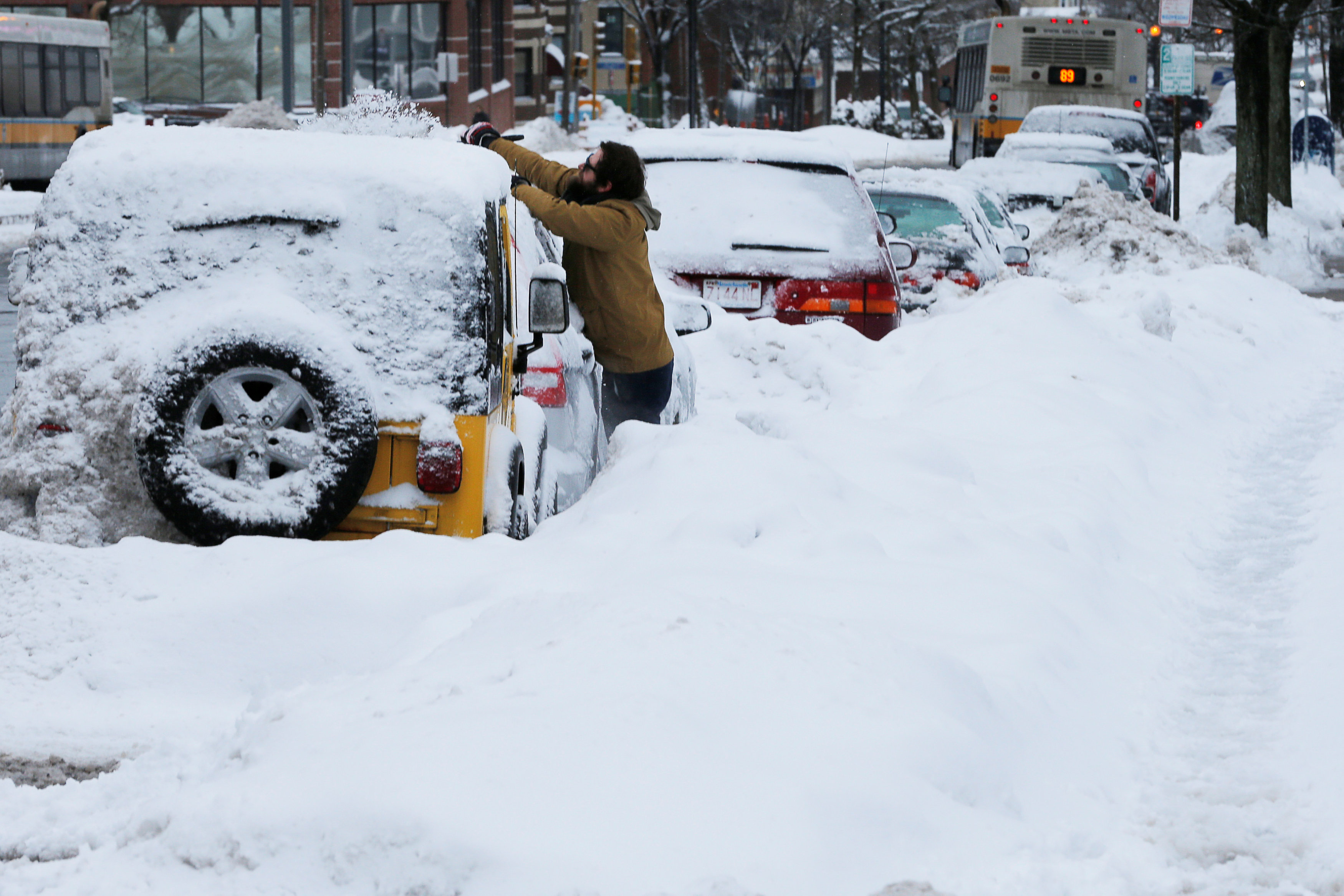 A man clears snow off his vehicle following a winter snow storm in Somerville