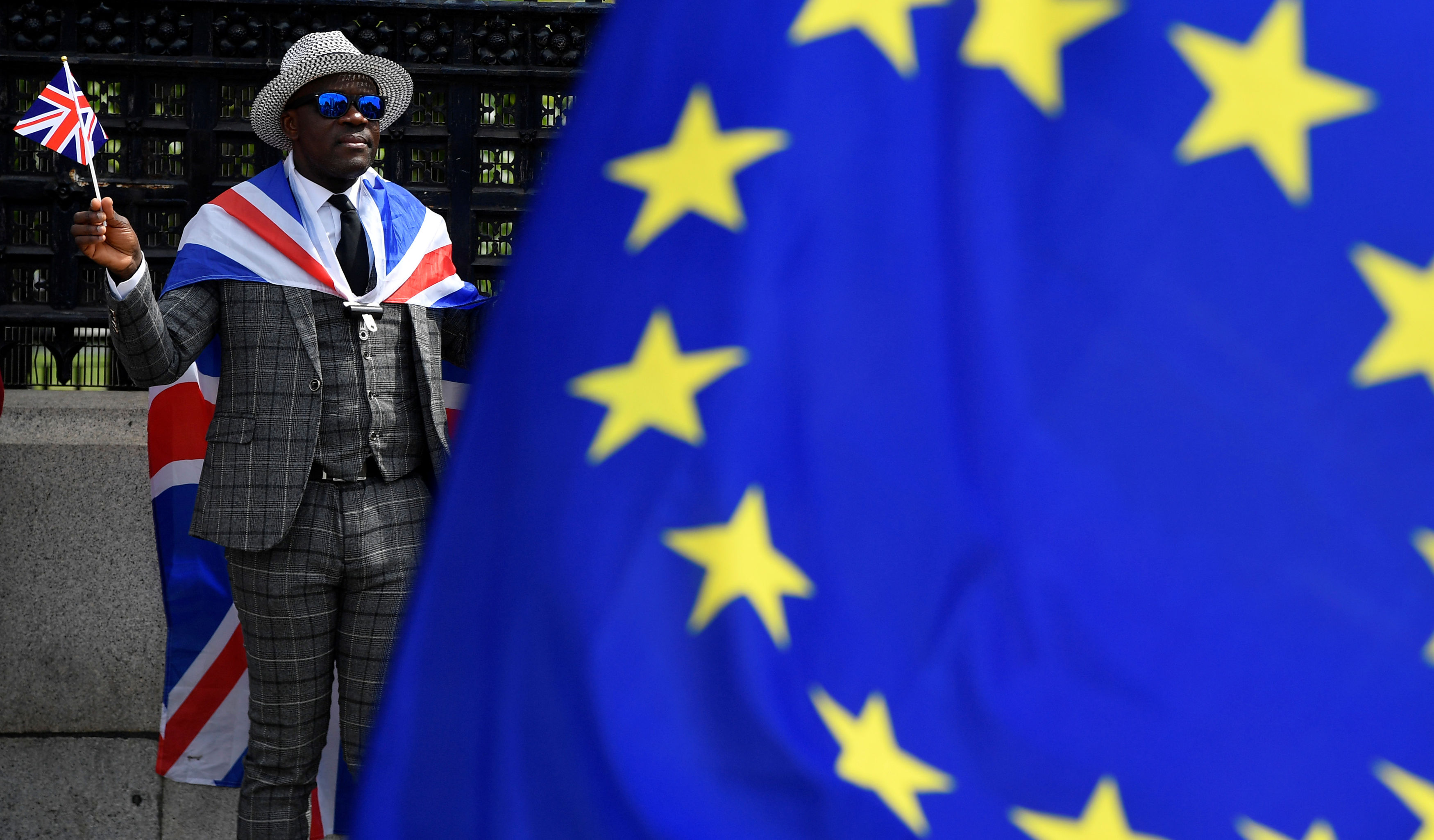 A pro-Brexit protester stands behind an EU flag ahead of the forthcoming EU elections, outside of the Houses of Parliament in London