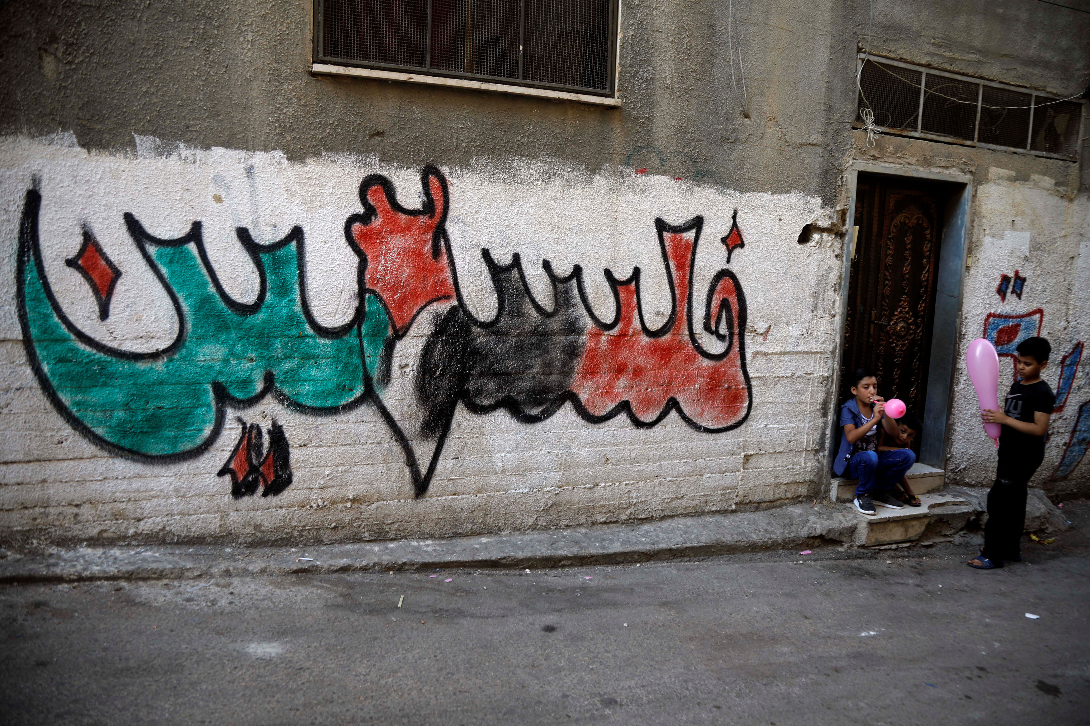 Palestinian boys play near a graffito reading: 