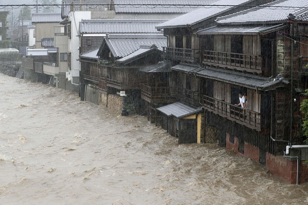 Men watch the swollen Isuzu River due to heavy rain caused by Typhoon Hagibis in Ise