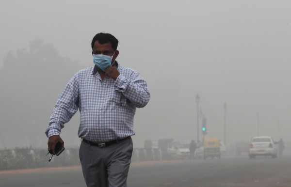 A man wearing a mask walks on a smoggy morning in New Delhi