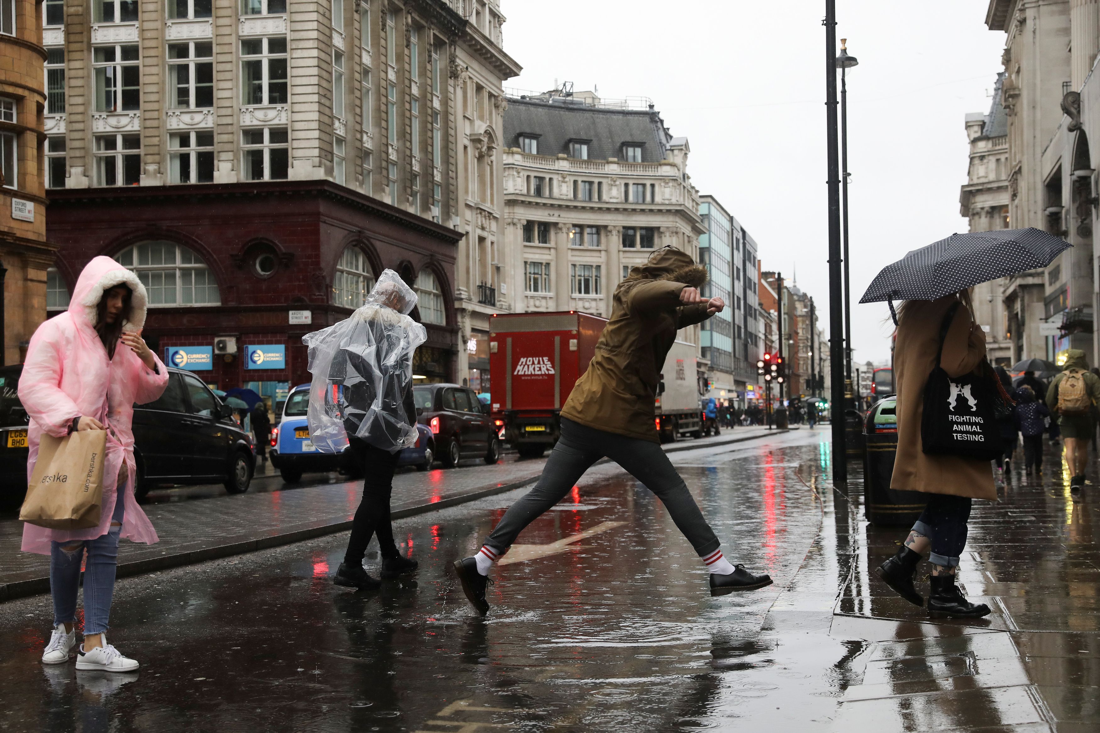 Pedestrians try to avoid a puddle as they walk down Oxford Street in London