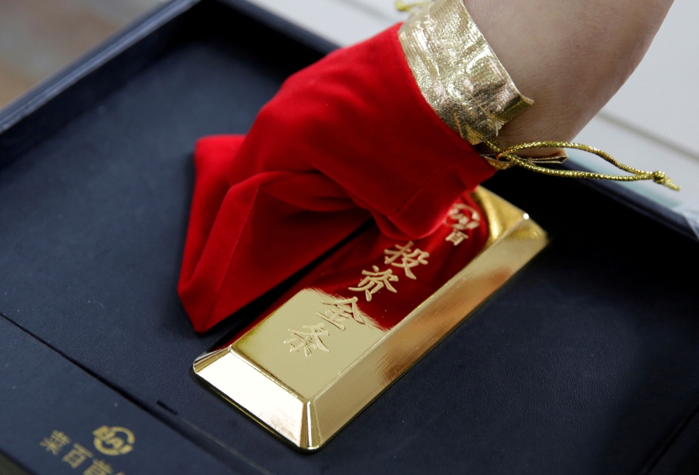 FILE PHOTO: A sales assistant displays a 1000 gram gold bar as an investment for a customer at Caibai Jewelry store in Beijing