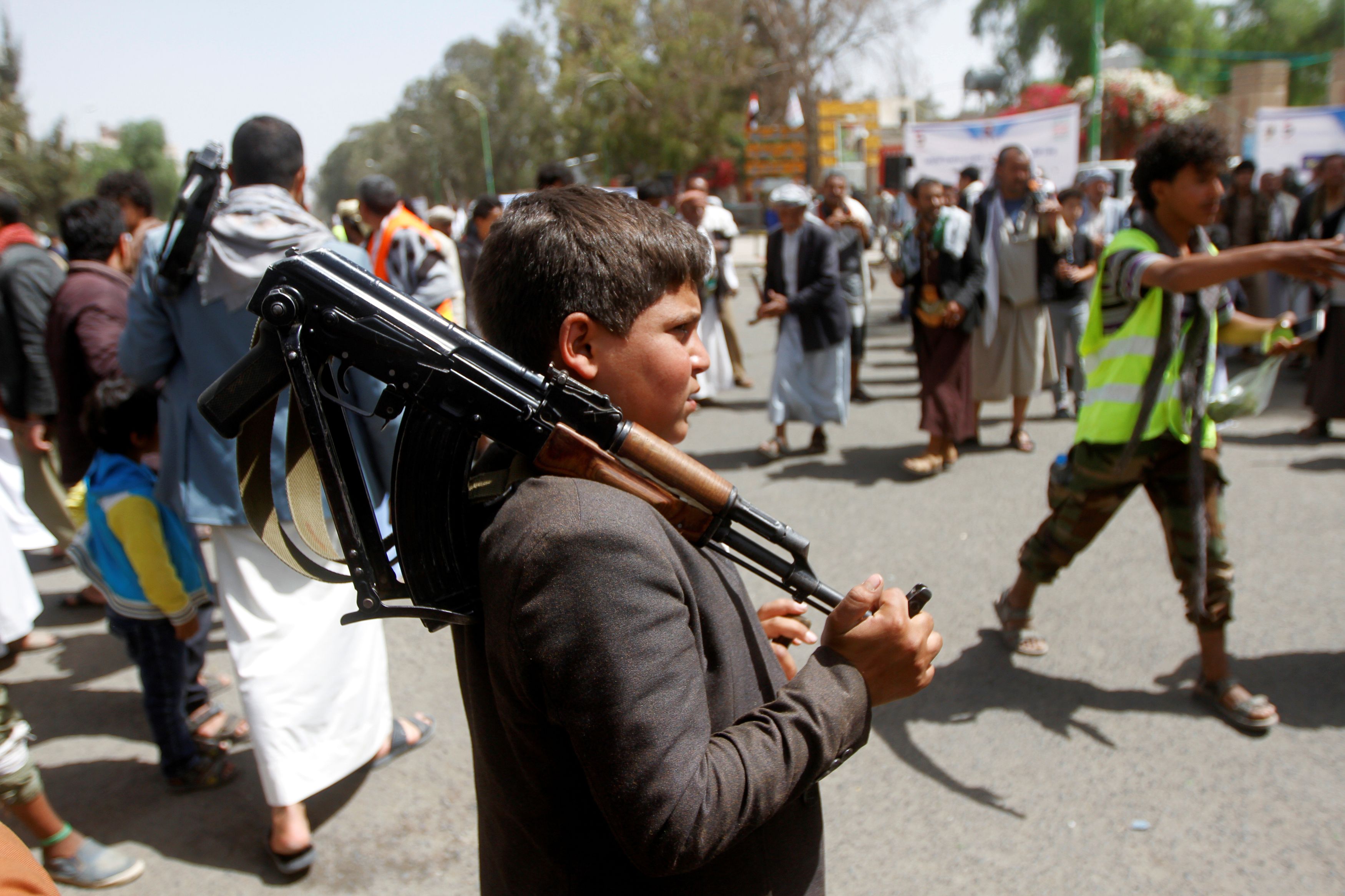 A boy carries a weapon as he and Houthi supporters are seen during a gathering in Sanaa