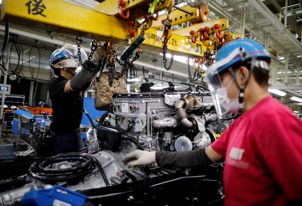 FILE PHOTO: Employees wearing protective face masks and face guards work on the automobile assembly line during the outbreak of the coronavirus disease (COVID-19) at the Kawasaki factory of Mitsubishi Fuso Truck and Bus Corp. in Kawasaki, Japan
