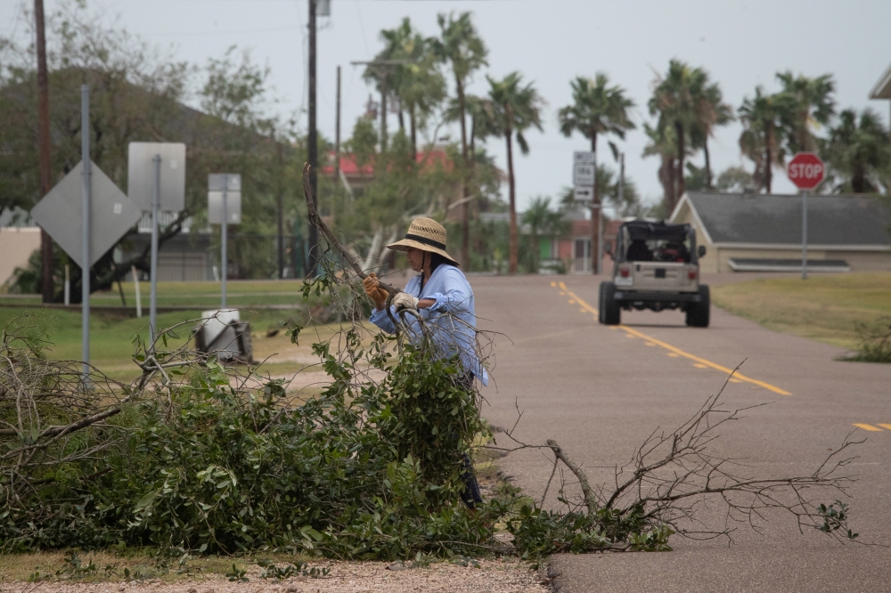 A resident clears debris after returning to her home in the aftermath of Hurricane Hanna in Port Mansfield, Texas