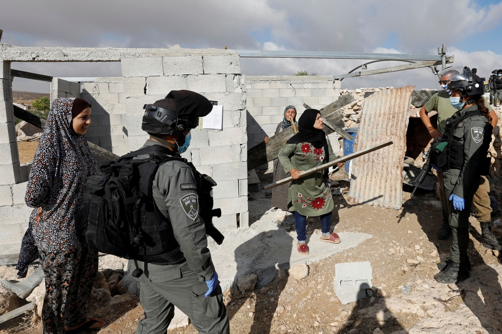 Palestinian woman argues with Israeli border police officers in the occupied West Bank