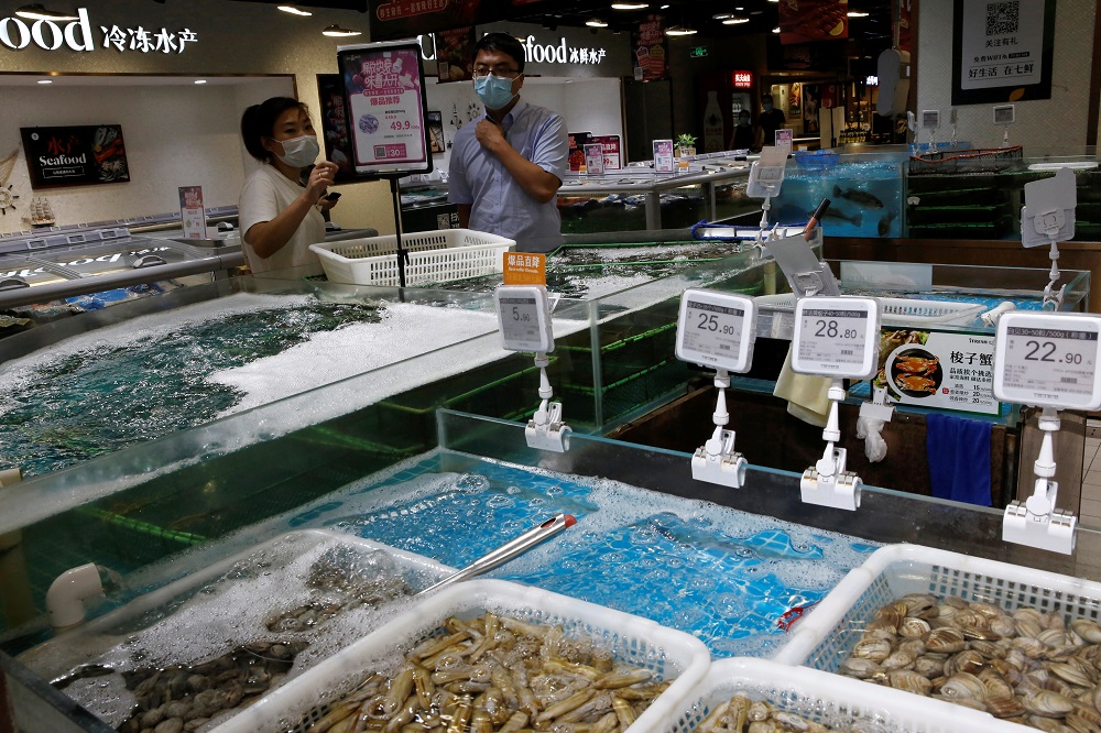 Staff member talks to a customer at a seafood section in JD.com's 7Fresh chain, following new cases of coronavirus disease (COVID-19) infections in Beijing