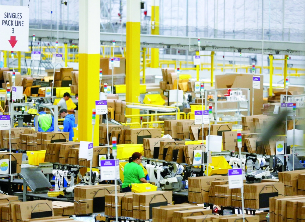 FILE PHOTO: Employees work at pack stations at the Amazon fulfillment center in Kent