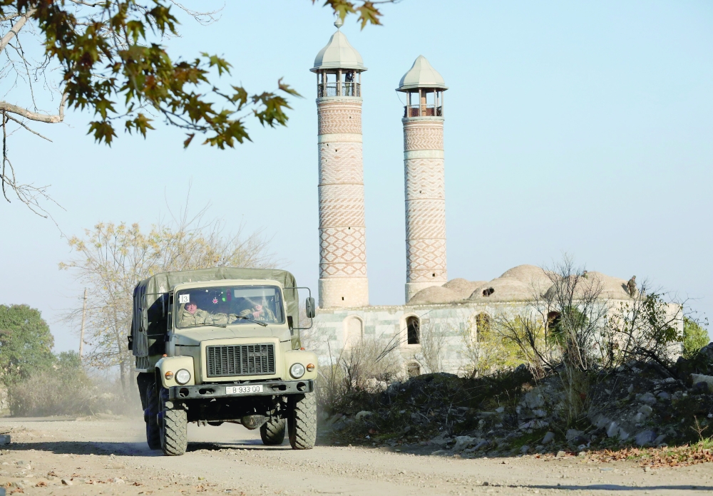 Azerbaijani service members drive a truck near a mosque in Agdam
