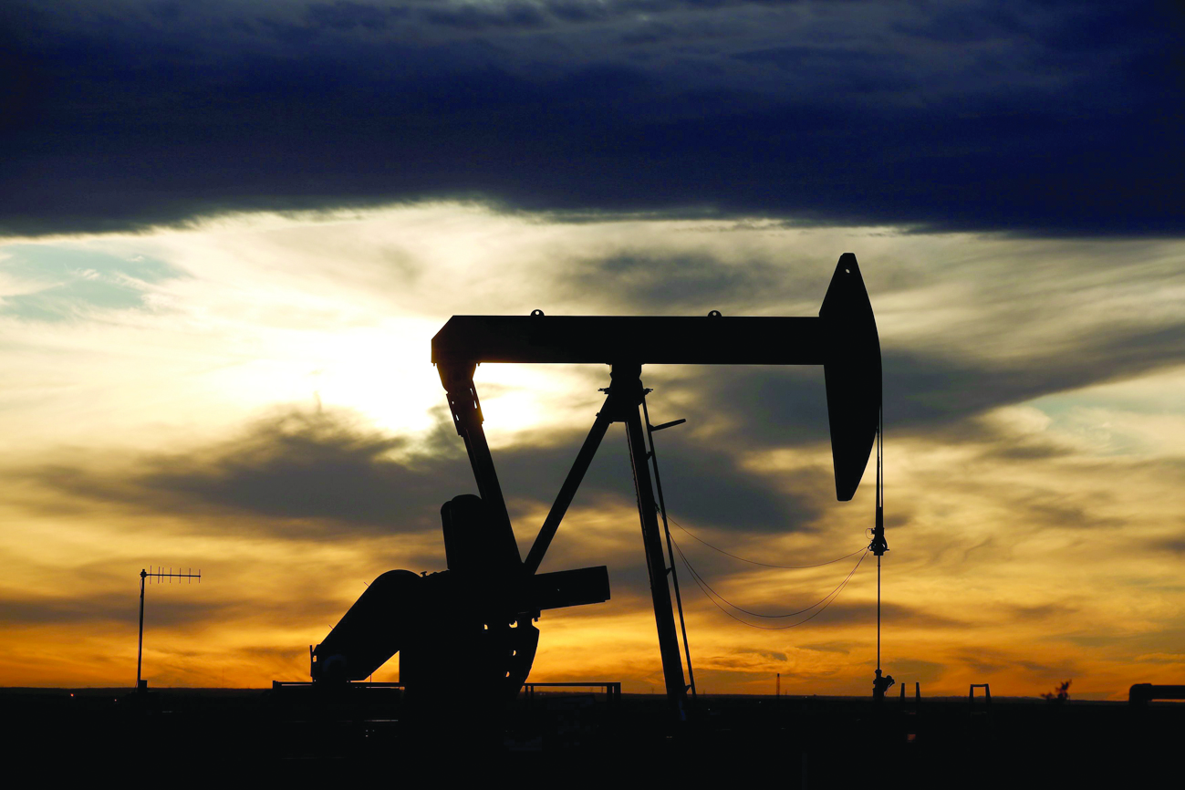 FILE PHOTO: The sun sets behind a crude oil pump jack on a drill pad in the Permian Basin in Loving County